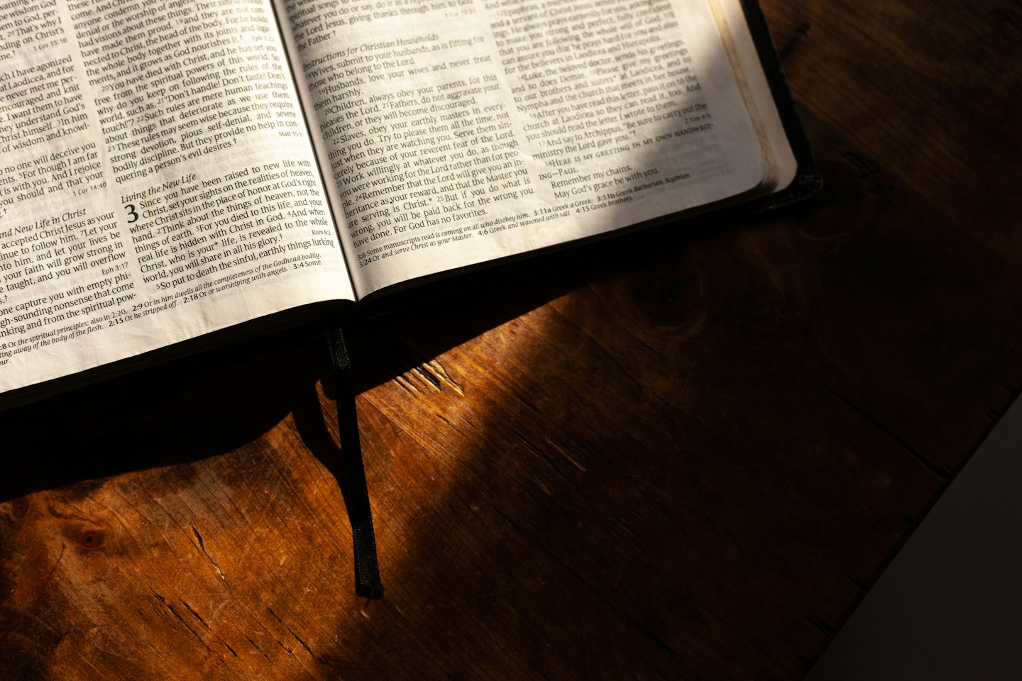 An open Bible rests on a rustic wooden table.